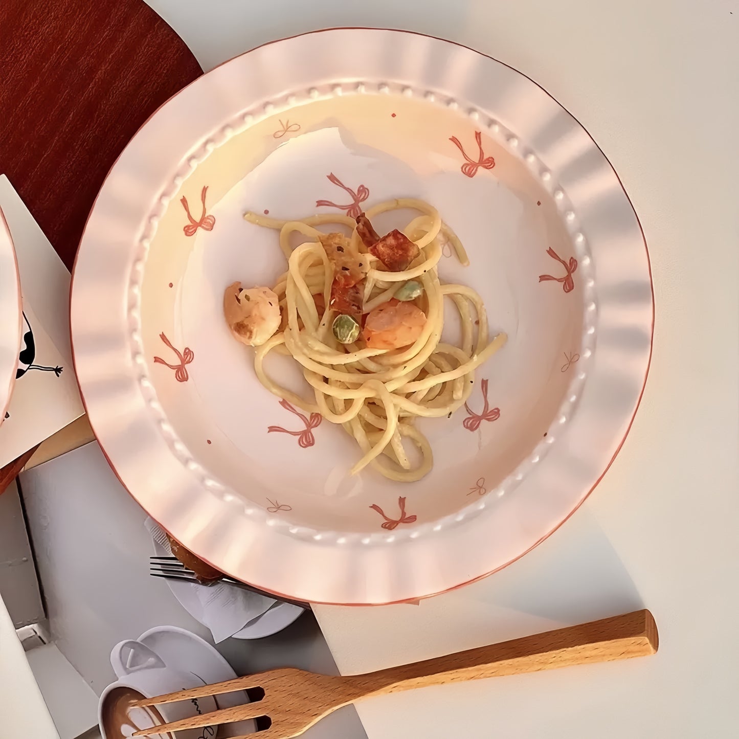 Plate of spaghetti with seafood on a decorative plate with a fork and knife.
