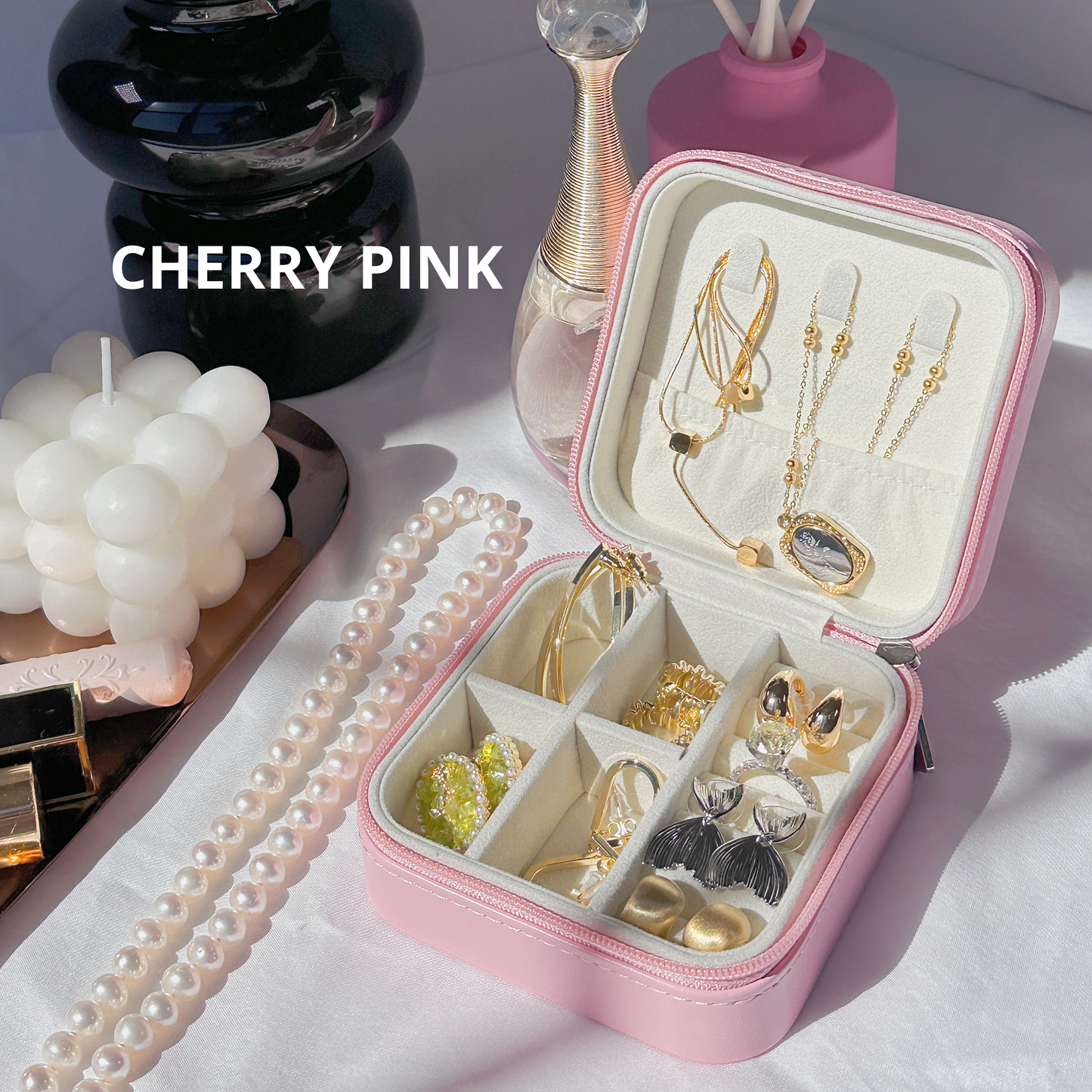 Stylish pink jewelry organizer placed next to a suitcase, highlighting travel-friendly portability