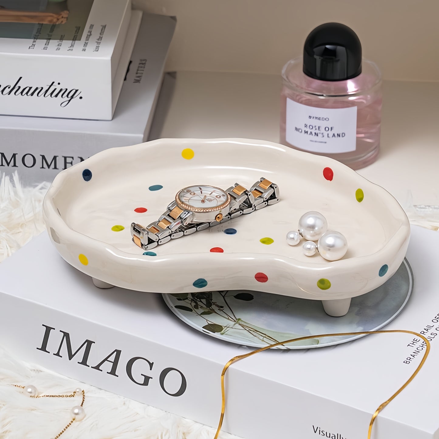 Decorative polka dot tray on a dresser organizing small trinkets and jewelry.