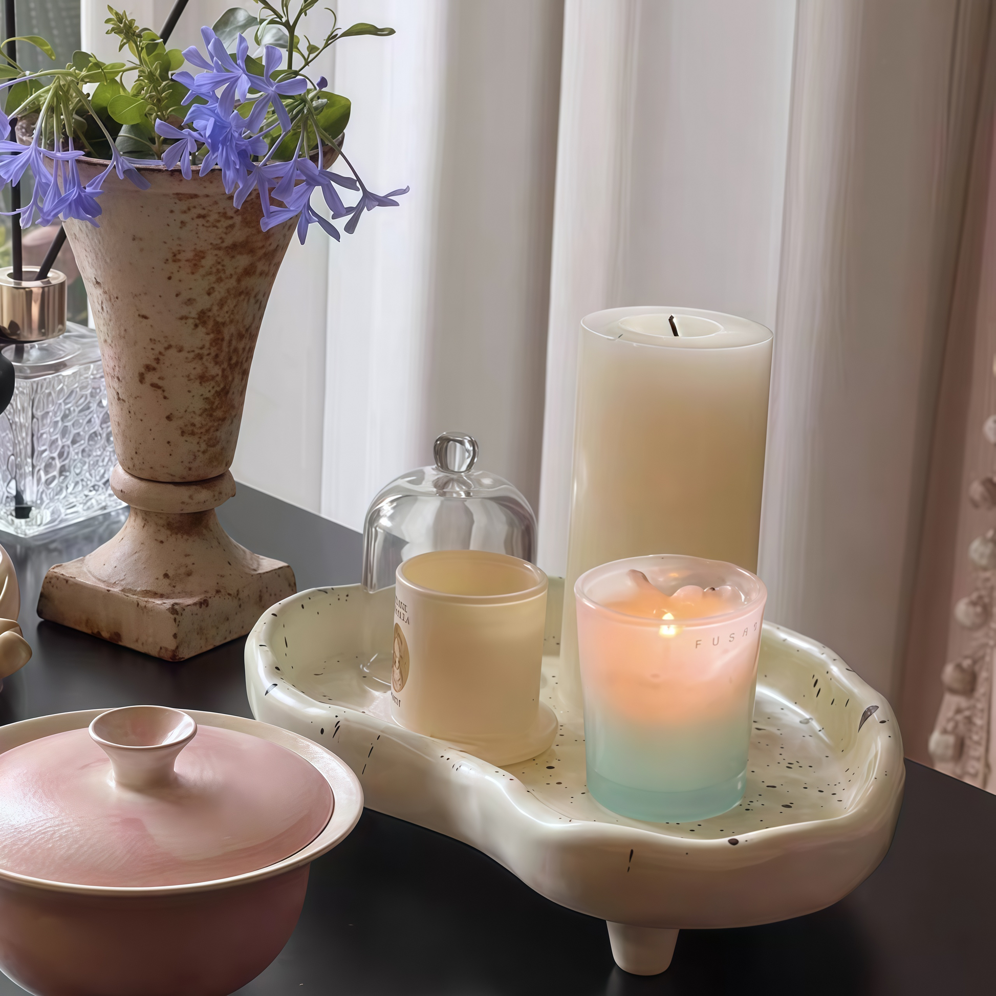 Decorative splatter tray organizing trinkets, jewelry, and small items on a dresser.