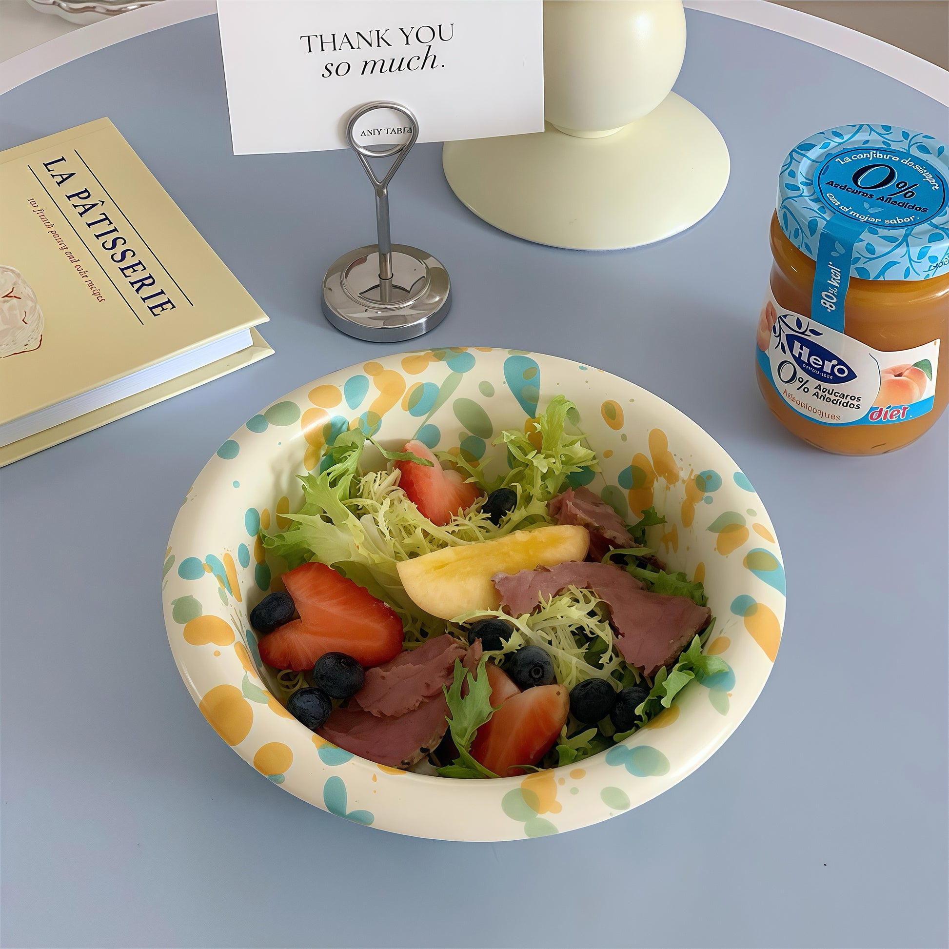 A large, colorful salad with mixed greens, vegetables, and chicken in a splatter-patterned bowl.