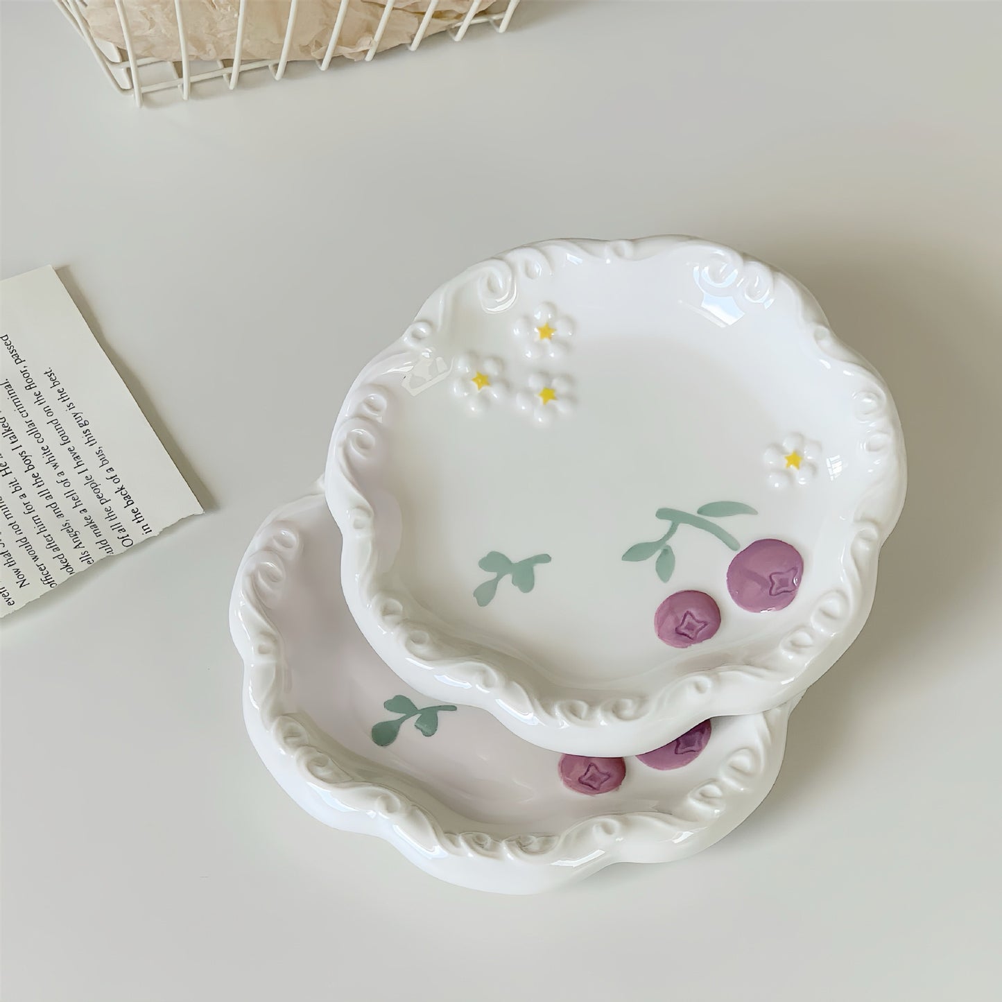 Set of two decorative ceramic plates with floral designs on a light surface.