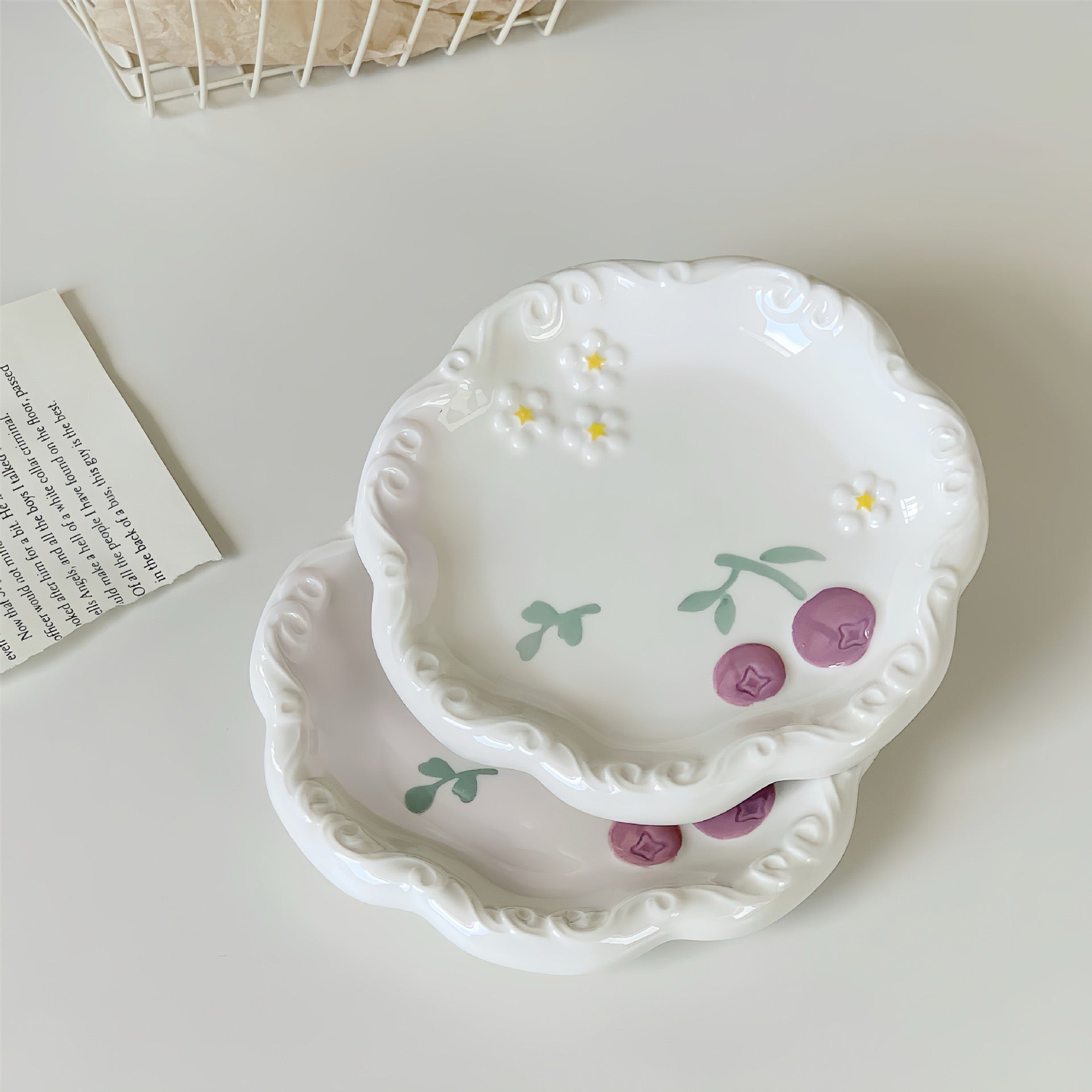 Set of two decorative ceramic plates with floral designs on a light surface.