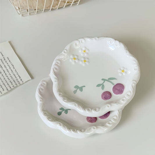 Set of two decorative ceramic plates with floral designs on a light surface.