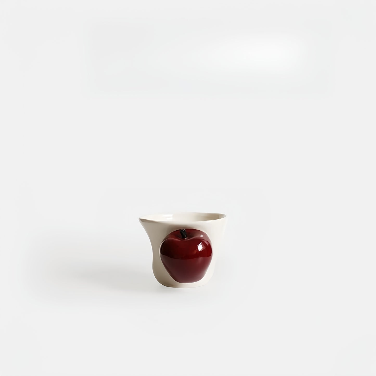 Hand-painted apple handle ceramic cup on white background, showing ergonomic contour.