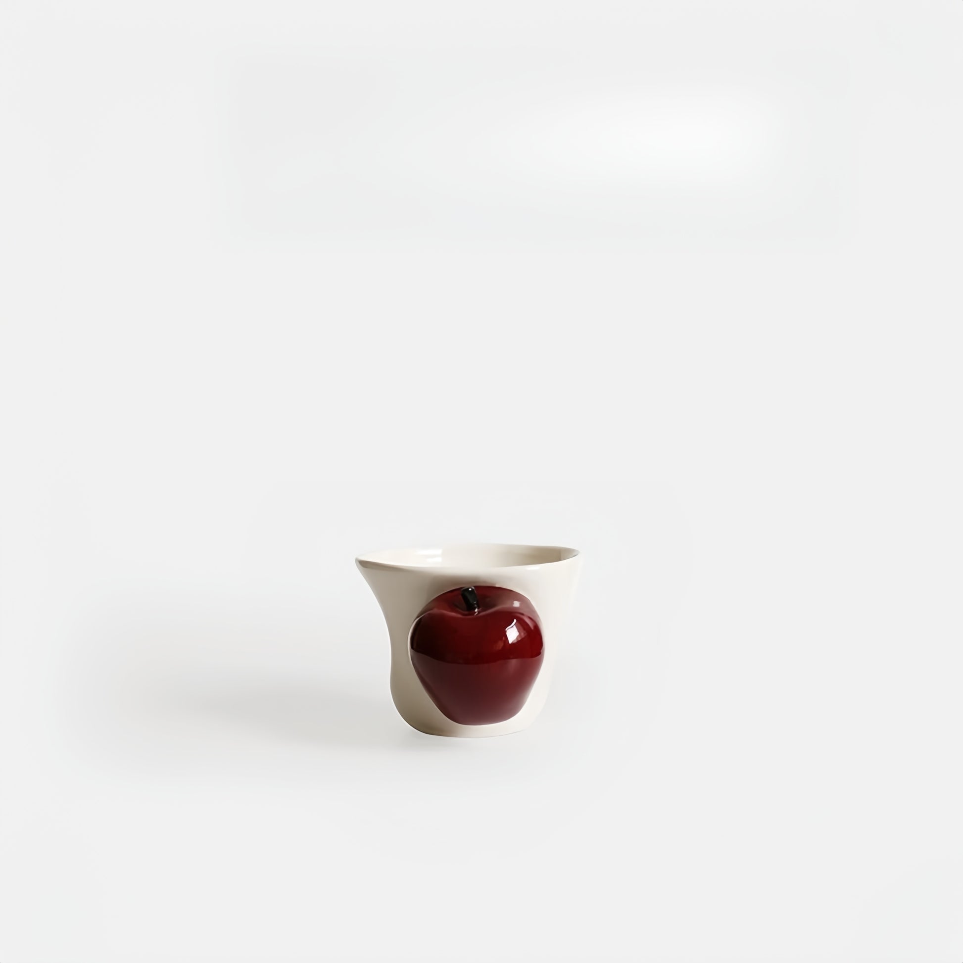 Hand-painted apple handle ceramic cup on white background, showing ergonomic contour.