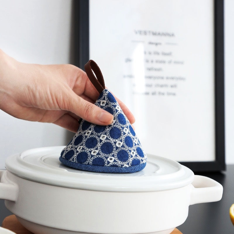Heat-resistant cotton pot cap securely covering a cast iron skillet lid, preventing burns during cooking.
