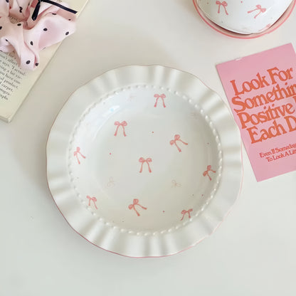 White plate with pink bow patterns on a light surface with a motivational card.