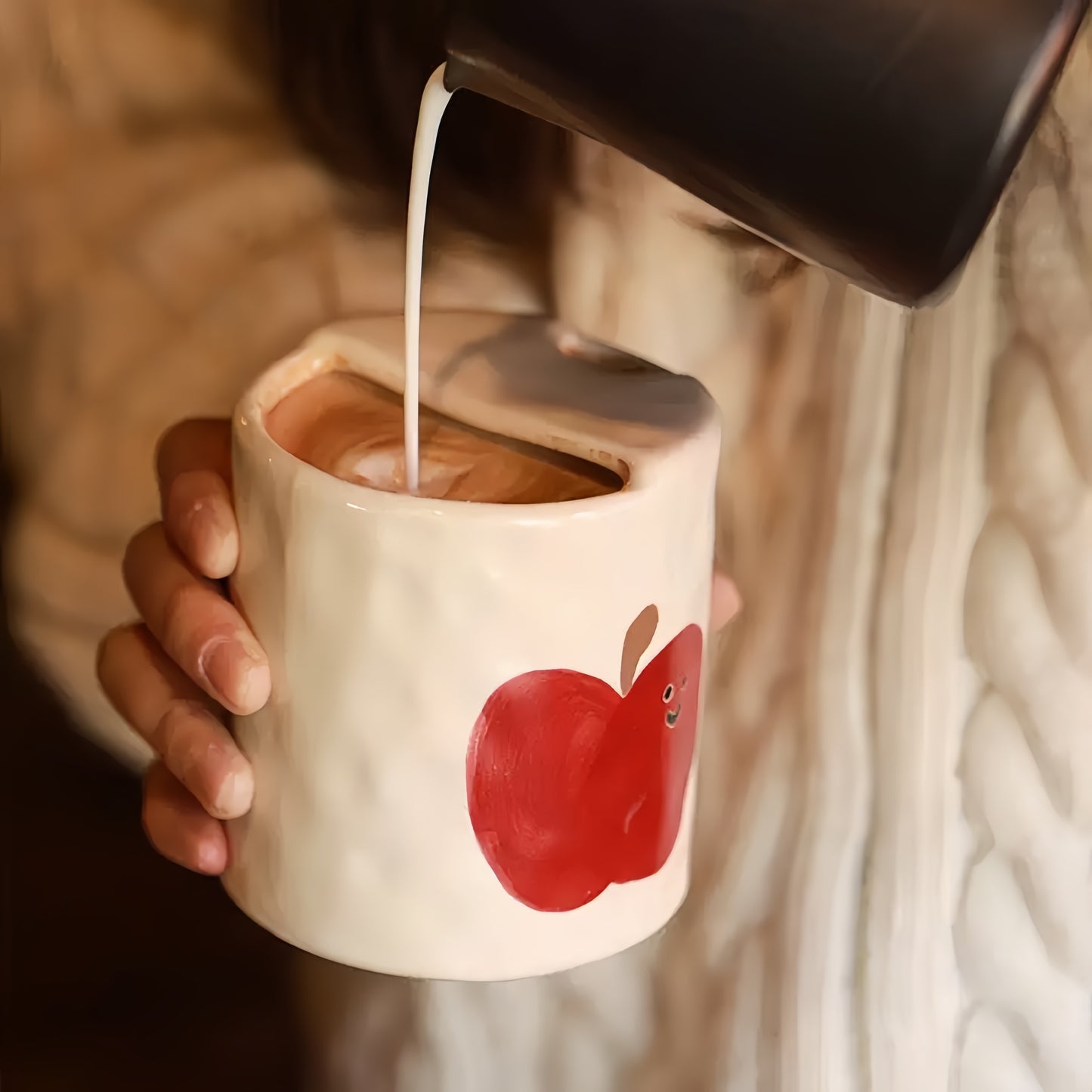 Person holding the Happy Apple mug filled with coffee, demonstrating its portability and style.