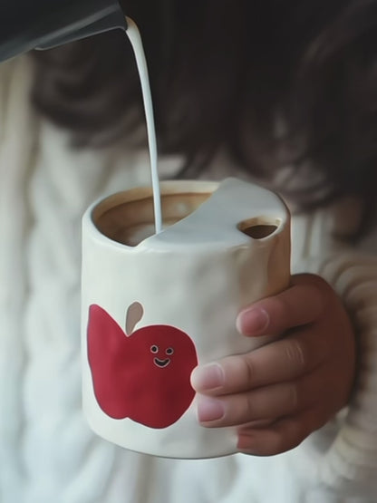 A set of handmade ceramic travel mugs shown from different angles, highlighting the unique apple artwork.