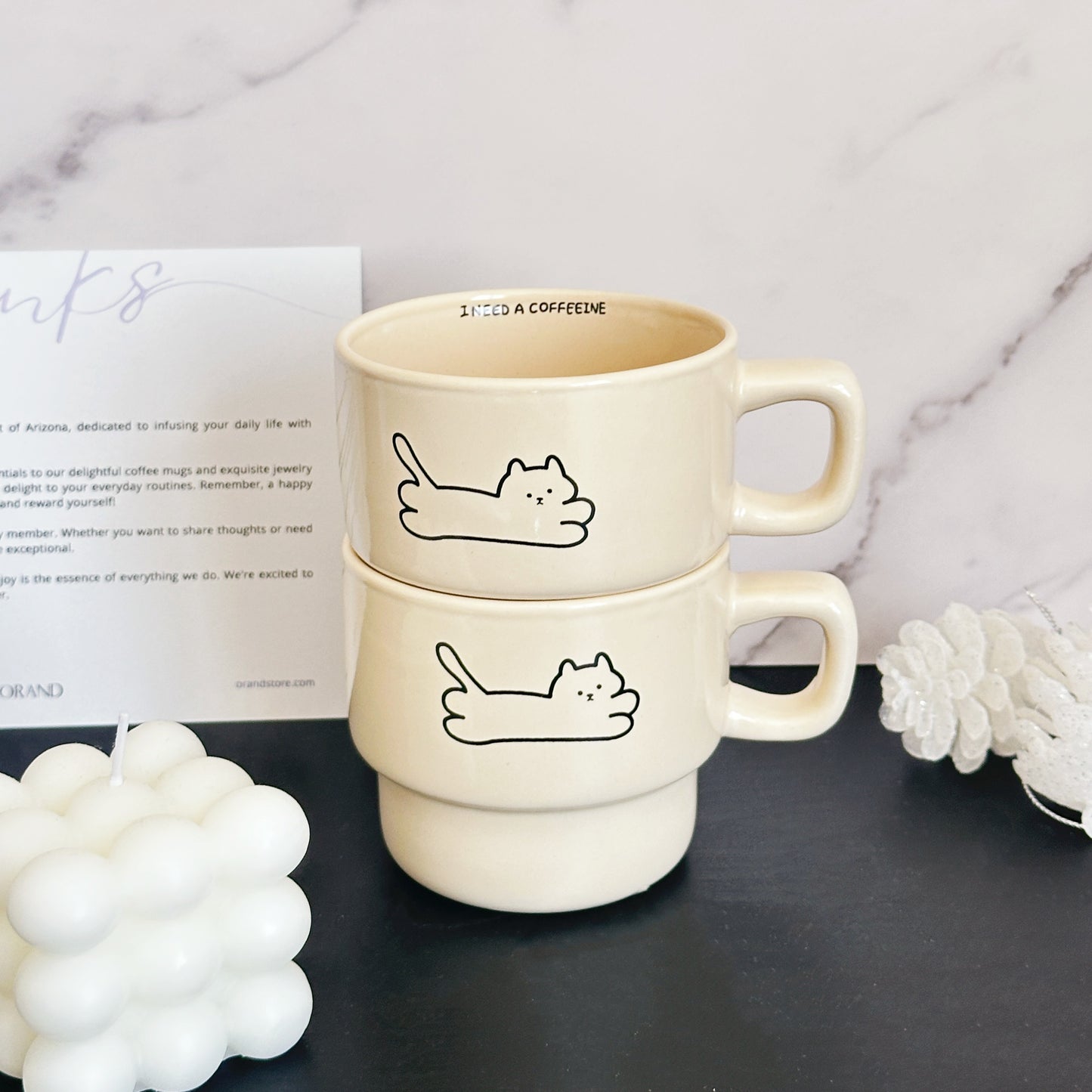A set of two stackable cat mugs stored neatly in a kitchen cupboard, saving space.
